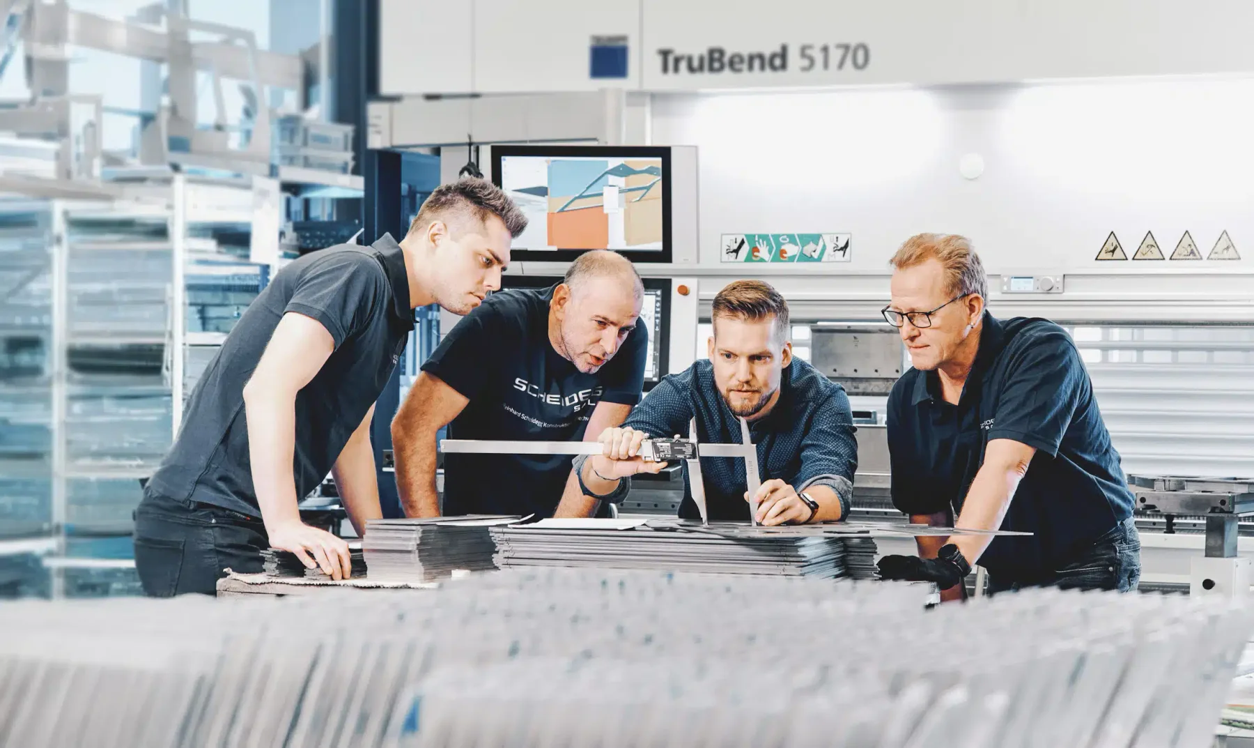 Kollegen bei Scheidegg Salem prüfen gemeinsam ein Bauteil an der Abkantpresse.